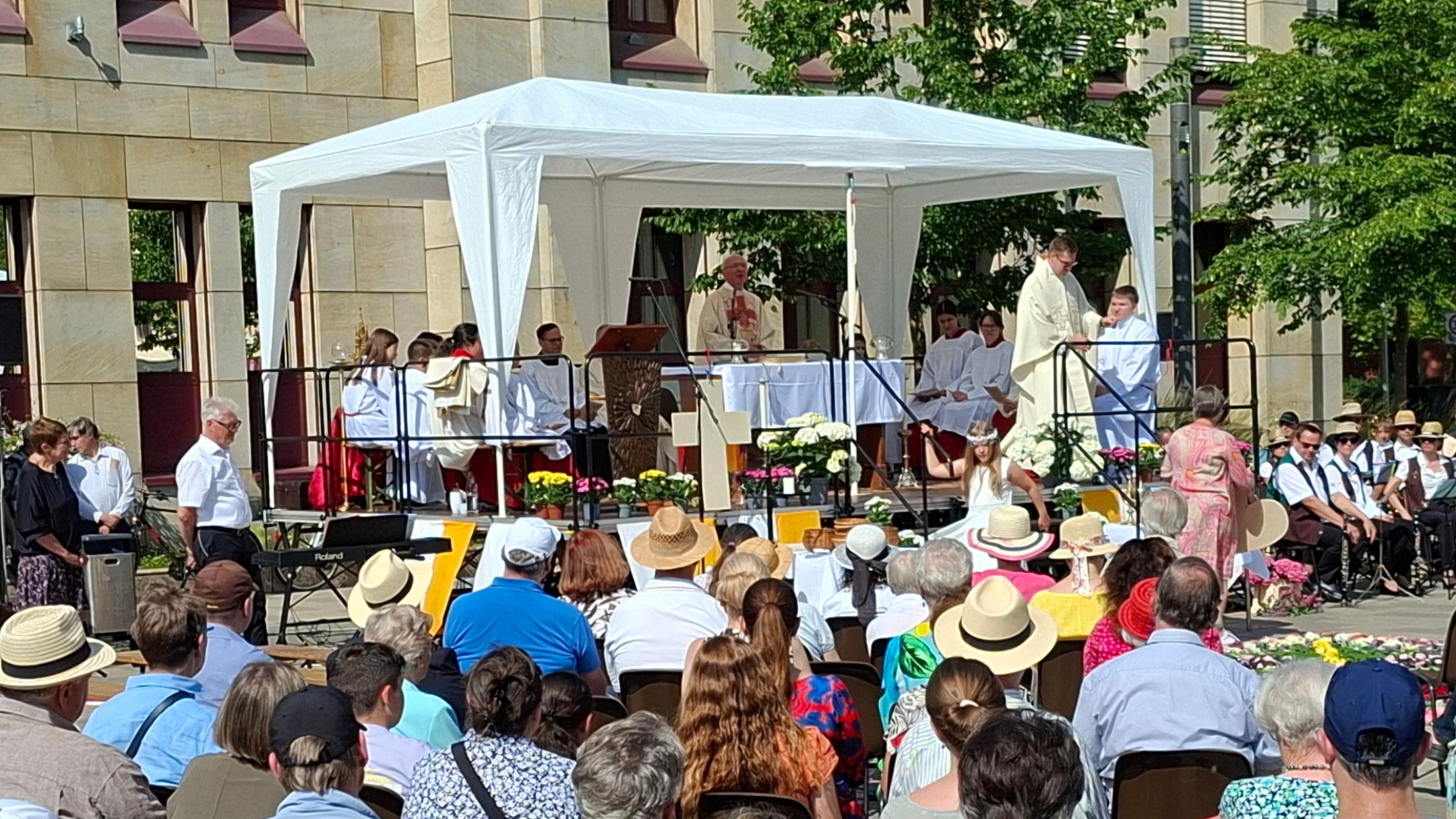 Das Bild zeigt den Blick auf den Altar auf dem Kornmarkt während des Fronleichnamgottesdienstes 2025, davor die sitzenden Gottesdienstteilnehmer