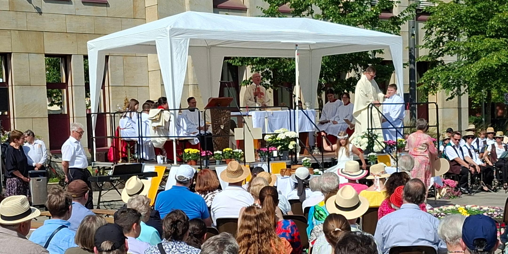 Das Bild zeigt den Blick auf den Altar auf dem Kornmarkt während des Fronleichnamgottesdienstes 2025, davor die sitzenden Gottesdienstteilnehmer