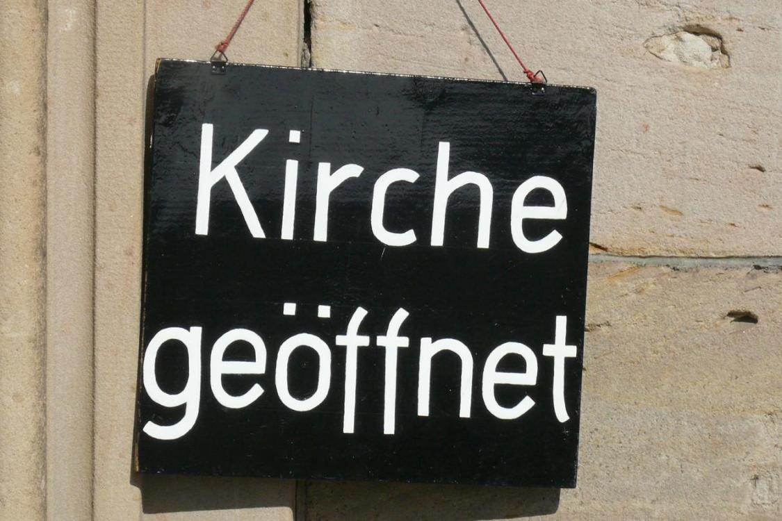 Ein Schild an der Wand mit der Aufschrift 'Kirche geöffnet'