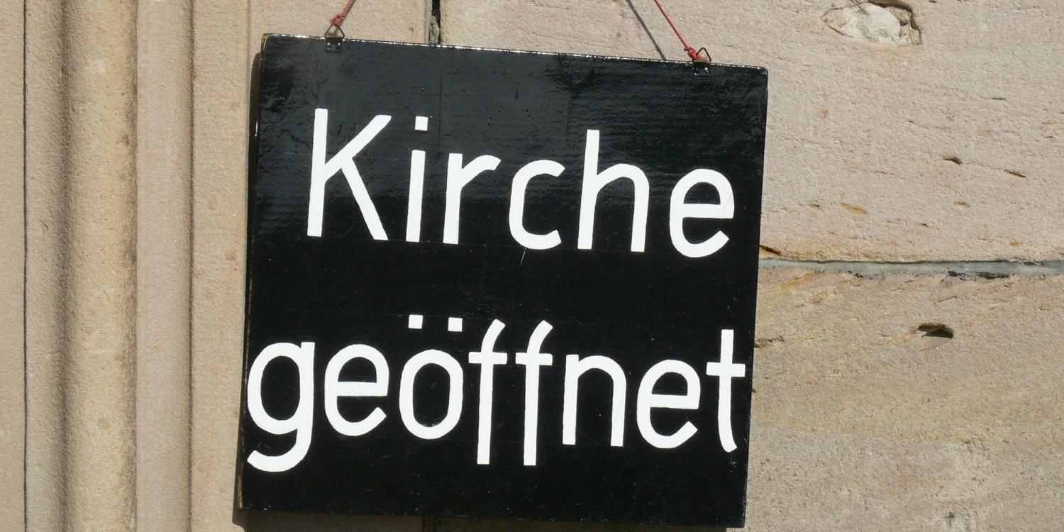 Ein Schild an der Wand mit der Aufschrift 'Kirche geöffnet'