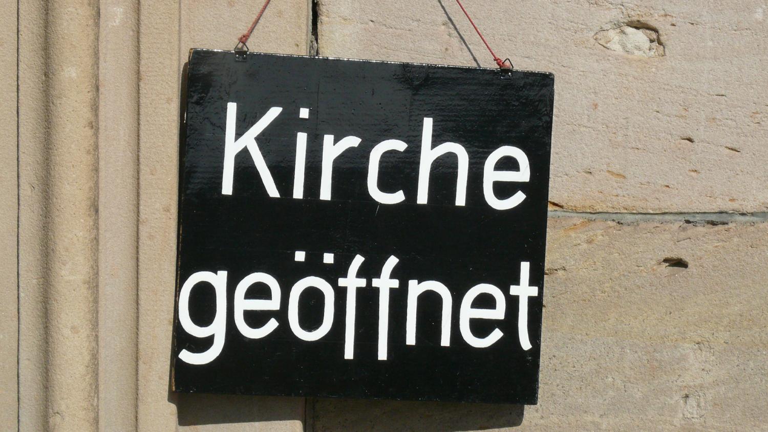 Ein Schild an der Wand mit der Aufschrift 'Kirche geöffnet'