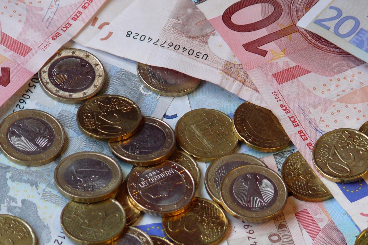 Das Bild zeigt Geldscheine und Münzen, die auf einer Unterlage liegen.