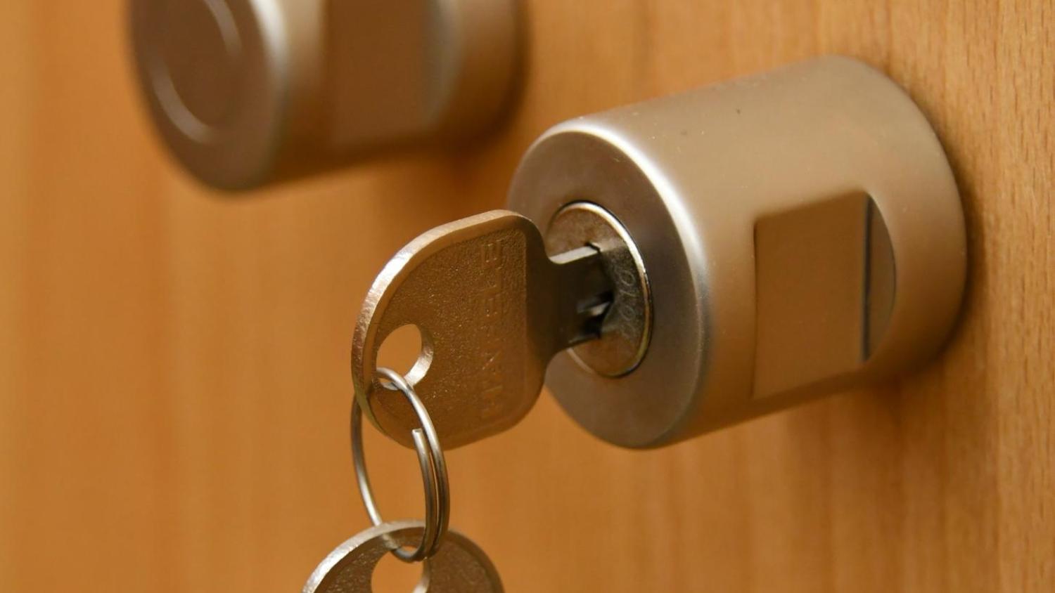 Das Bild zeigt eine Holzfront mit aufgesetzem Schloss und eingestecktem Schlüssel