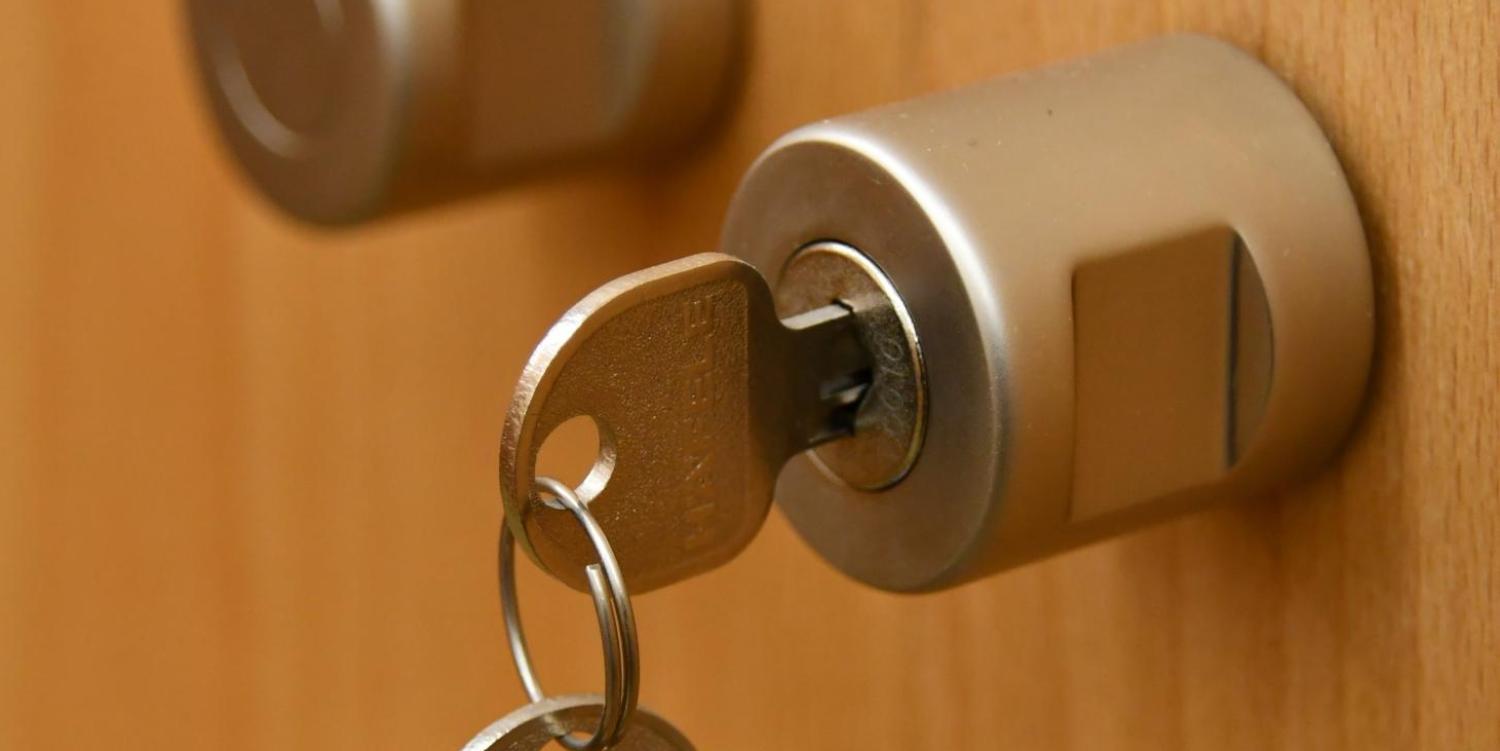 Das Bild zeigt eine Holzfront mit aufgesetzem Schloss und eingestecktem Schlüssel
